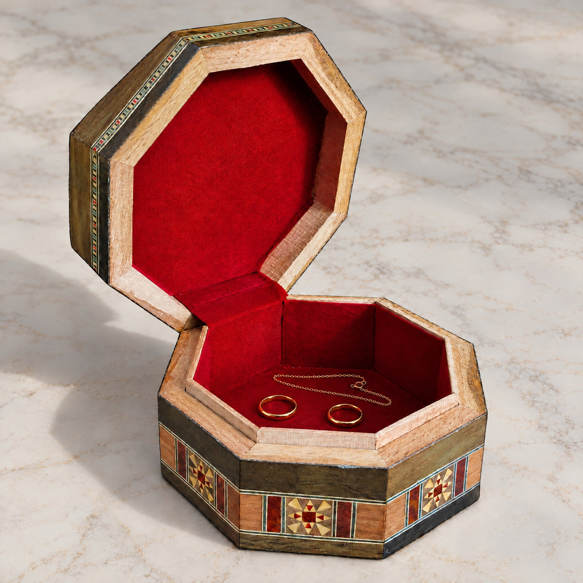 Radiant Mosaic Box open on marble, velvet-lined interior with two rings