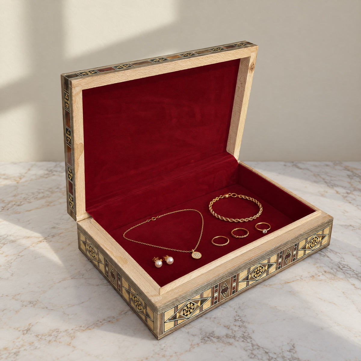 Majestic Mosaic Box, open, showing its wine-red velvet lining with a gold necklace, bracelet, rings and pearl earrings
