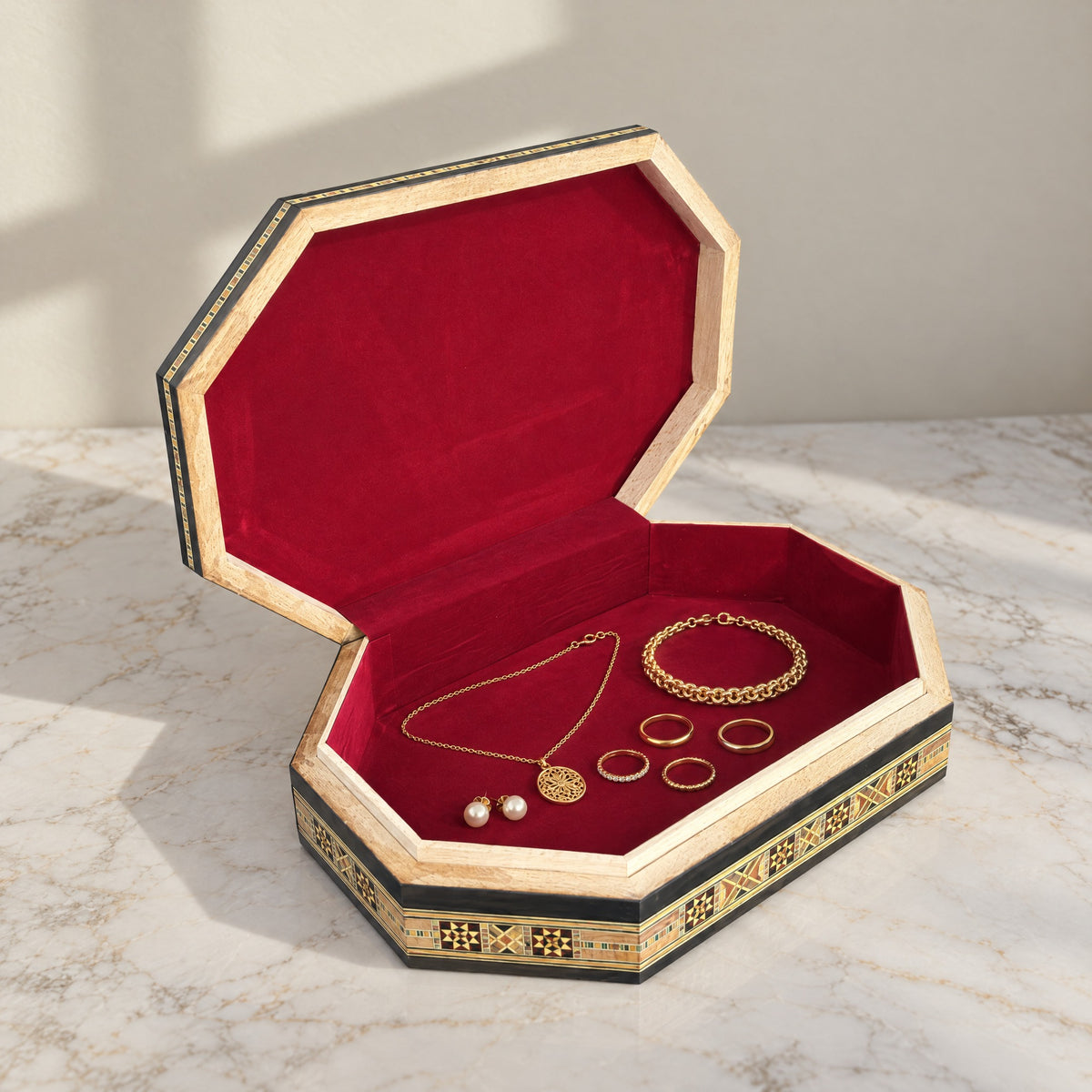 Sovereign Mosaic Box, open, showing its wine-red velvet lining with a gold necklace, bracelet, rings and pearl earrings