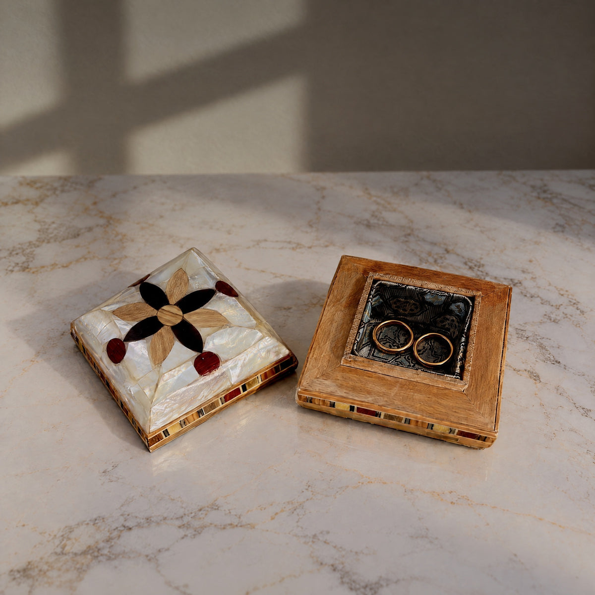 Keepsake Mu'ashak box open on marble, showing the brocade-lined base with two rings beside its lid