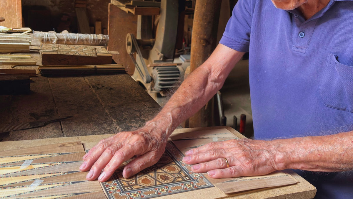 Hands laying a Damascene mosaic panel at the workbench in Abu Boutros's workshop in Damascus
