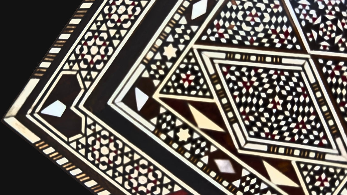 Close-up of Damascene mosaic inlay with mother-of-pearl and fine wood patterns on a dark ground