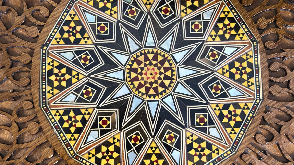 Close-up of a Damascene mosaic star inlaid in wood and mother-of-pearl, inside a carved frame