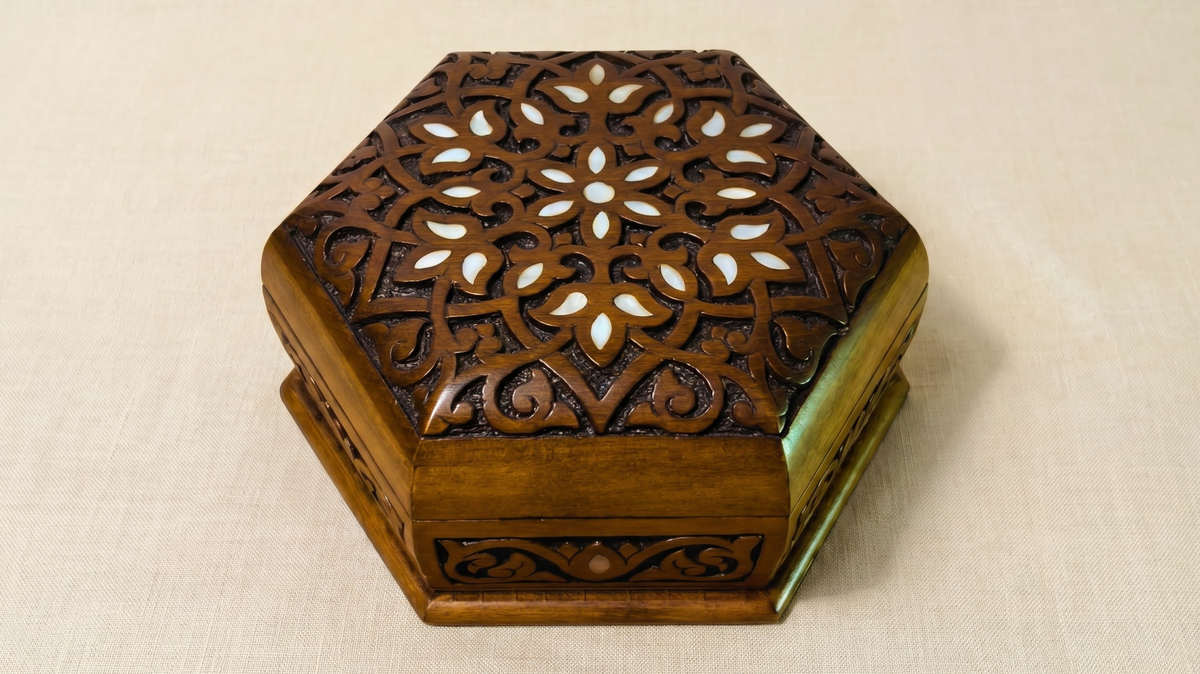 Hexagonal hand-carved wooden box with mother-of-pearl inlay, on cream linen