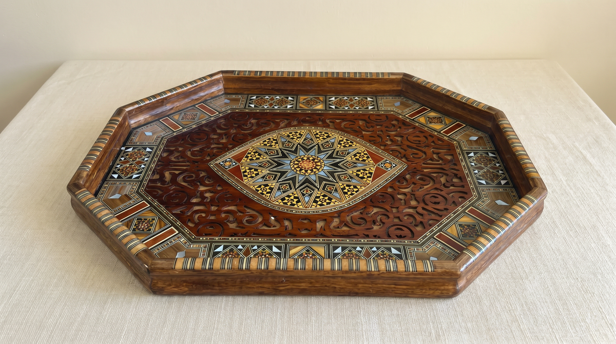 Octagonal Damascene tray with a carved center and a mosaic and mother-of-pearl border, on cream linen