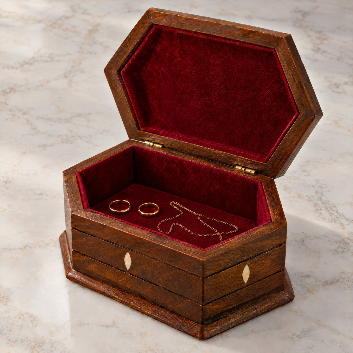 Legacy Carved Box open on marble, wine-red velvet lining with two rings and a chain