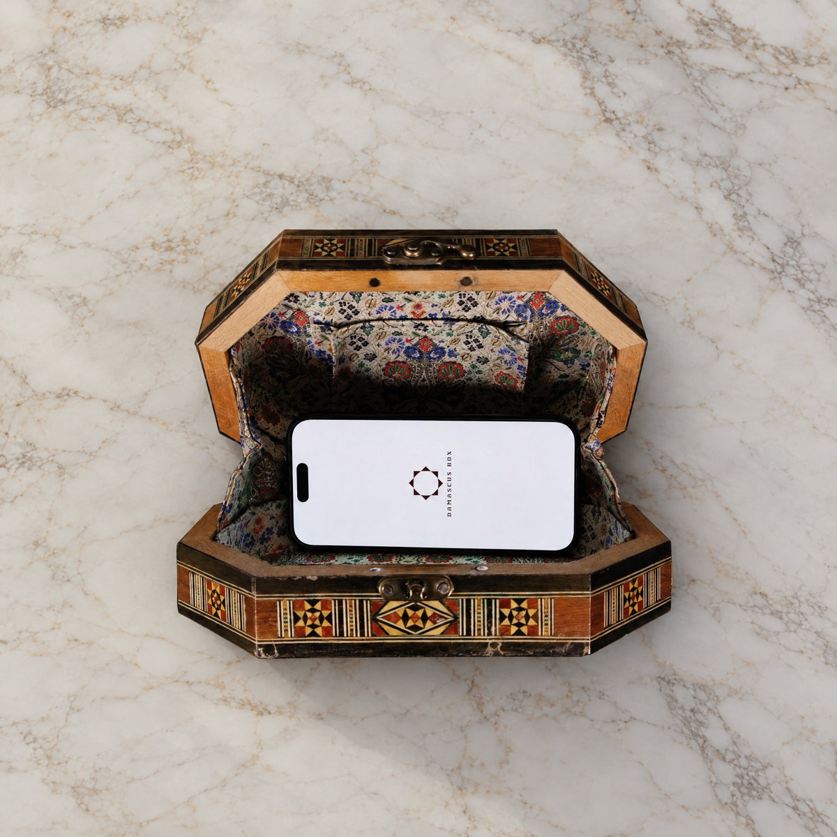 Qamar Damascene Clutch open on marble with a smartphone inside