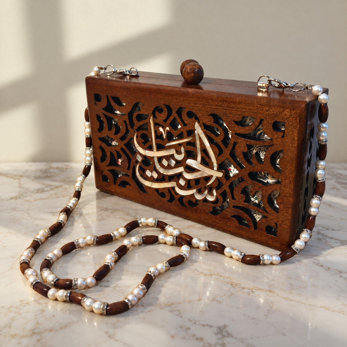Set El Habayeb Walnut Clutch on a white marble table in warm window light