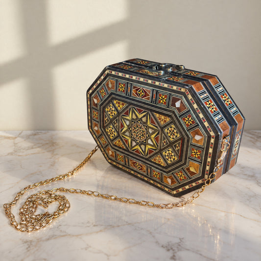 Qamar Damascene Clutch on a white marble table in warm window light