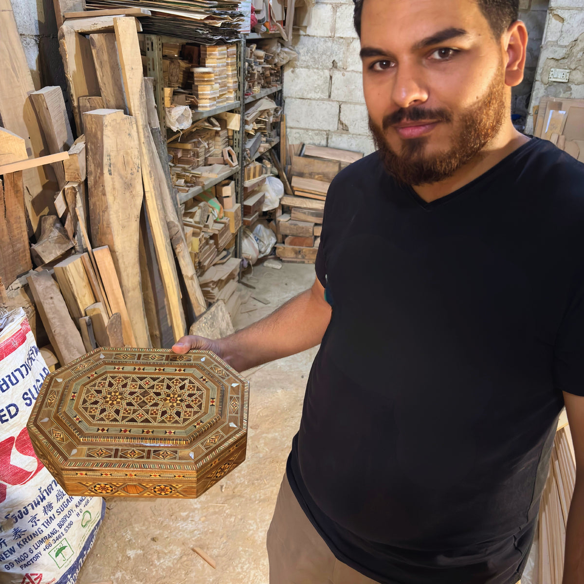Mohammad Tarek Al-Dahh holding a mosaic box in his workshop in Damascus