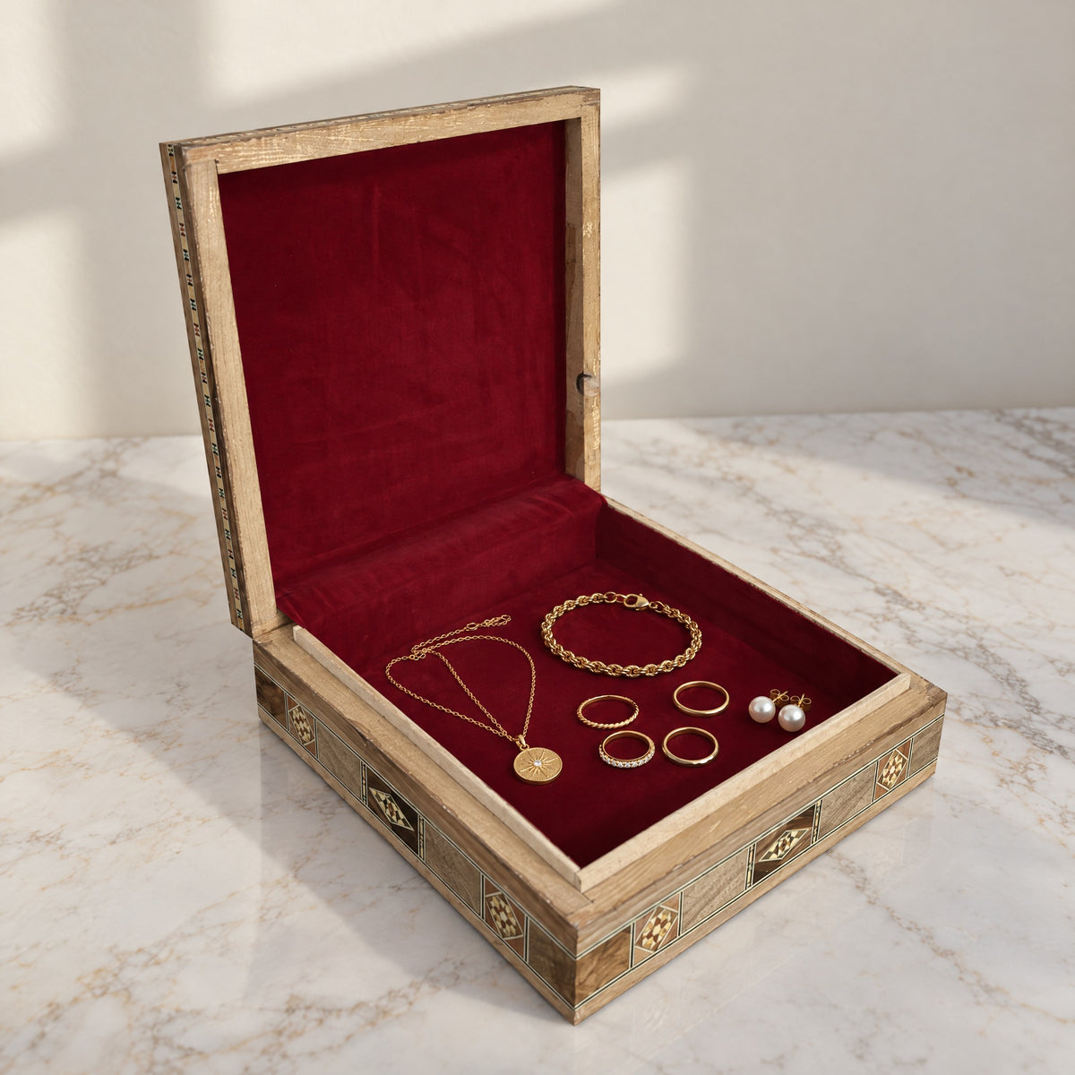 Graceful Mosaic Box, open, showing its wine-red velvet lining with a gold necklace, bracelet, rings and pearl earrings