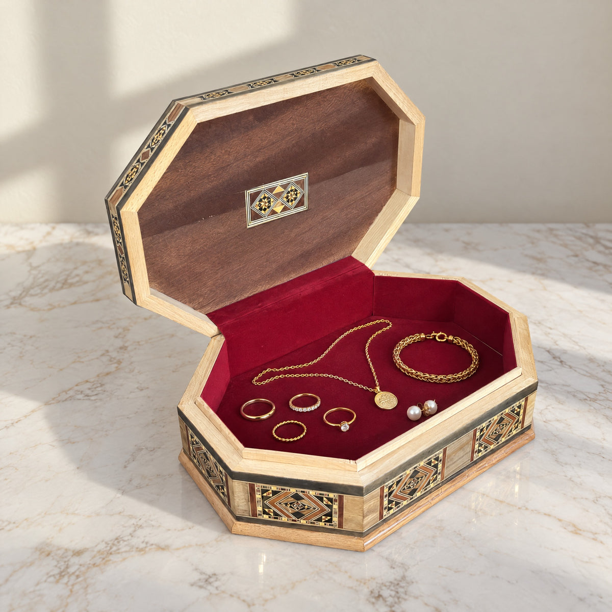 Resplendent Mosaic Box, open, showing its wine-red velvet lining with a gold necklace, bracelet, rings and pearl earrings