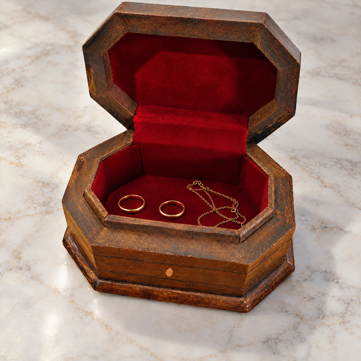 Artisan Carved Box open on marble, wine-red velvet lining with two rings and a chain