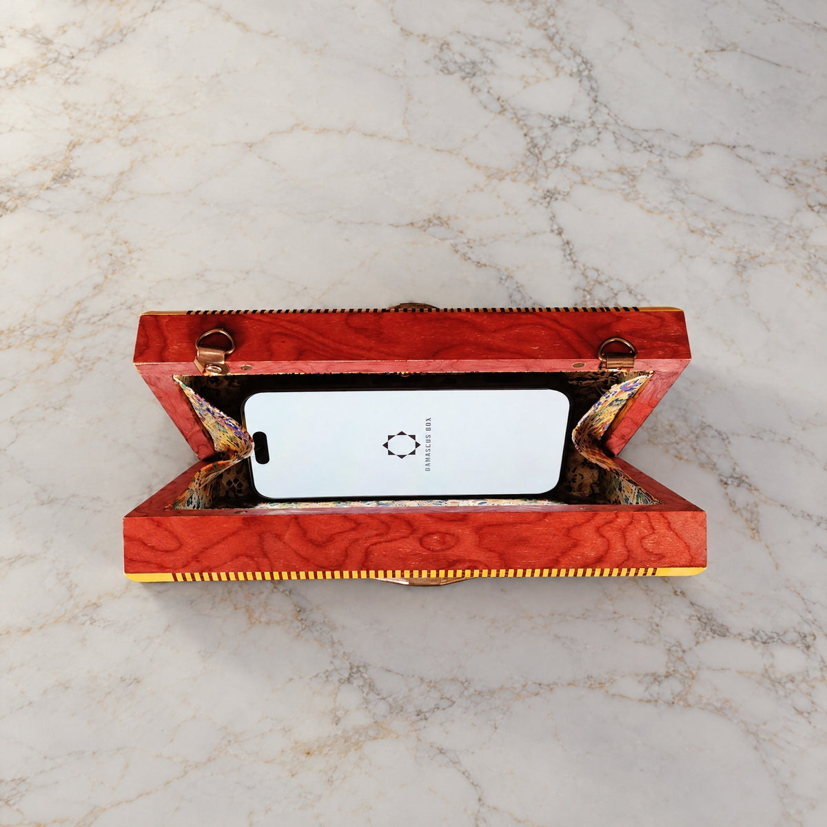 Noor Damascene Clutch open on marble with a smartphone inside
