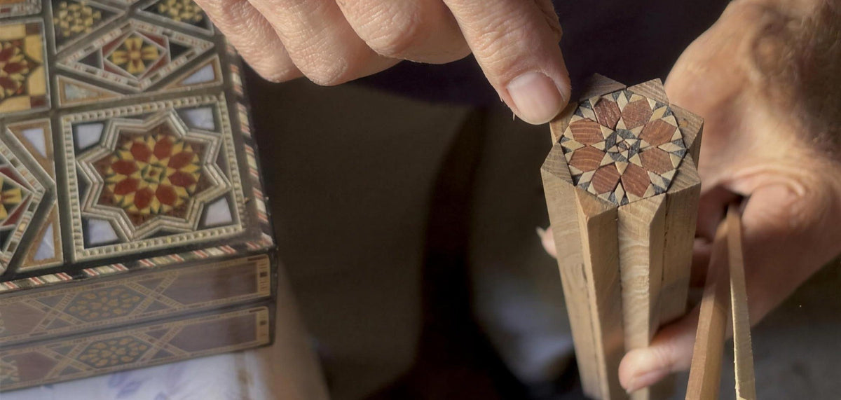Gabriel Al-Dayeh holds a bundle of wood rods whose end shows a mosaic star, in his workshop in Damascus