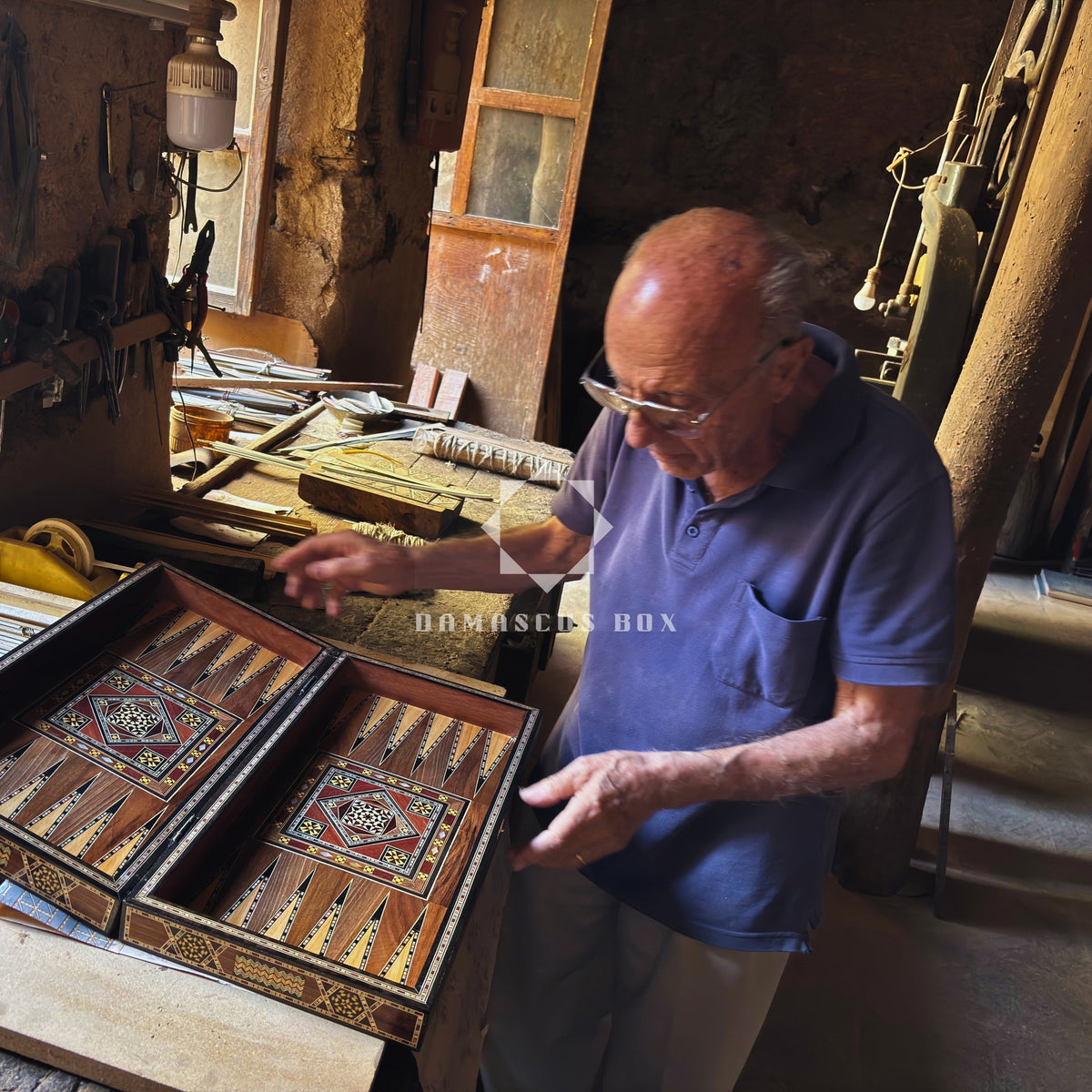 Damascus master artisan Gaby Al Dayeh in his workshop with a backgammon board